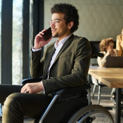 Young confident businessman in whellchair sitting in front of window